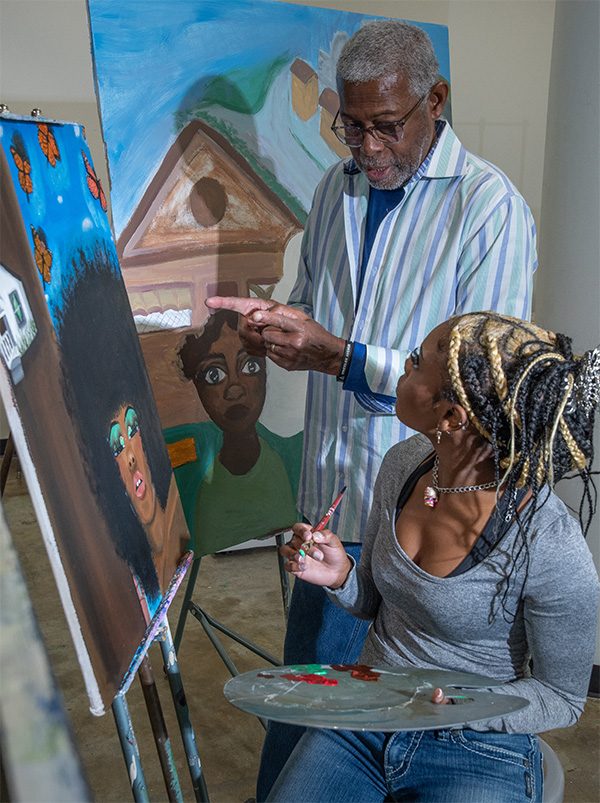 Floyd Newsum Jr. critiquing a painting in progress with an artist